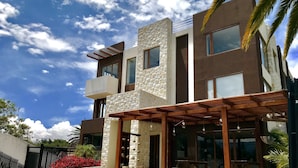 A modern two-story building with a stone facade, large windows, and a covered outdoor seating area. - Ilalo Garden Hotel & Restaurant (Tumbaco)