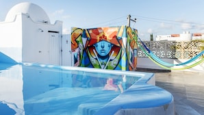 A pool with a colorful mural on the adjacent wall, a white building with a dome, and a hammock. - Valentina Suites by Las Flores (Playa del Carmen)