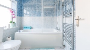 A modern bathroom with a bathtub, toilet, and shower area. - Lovely Apartment Angel (London)