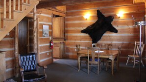 A log cabin interior with a dining area, wooden staircase, and a mounted animal hide. - Sugar Loaf Lodge & Cabins (Anaconda)