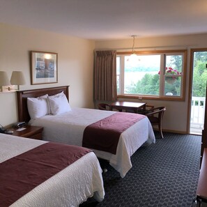 A hotel room with two beds, a desk, and a window with curtains.