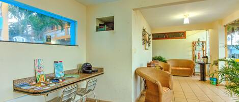 Una habitación con cocina, una mesa de comedor con sillas, un sofá y una ventana que ofrece vistas a palmeras.