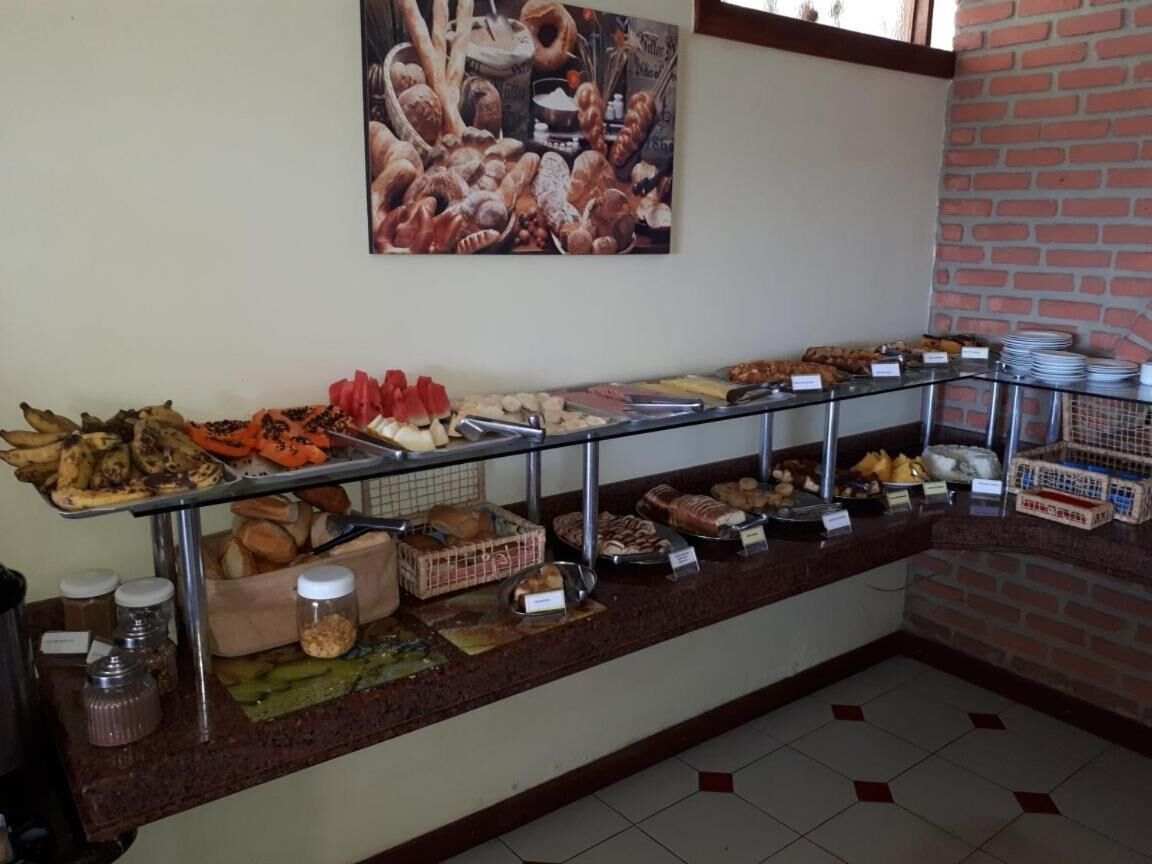 A buffet with various food items, including fruits, vegetables, and baked goods, displayed on a counter with a glass barrier.