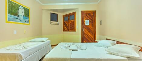 Habitación de hotel con dos camas individuales, un ventilador de techo, un cuadro en la pared y una puerta de madera.