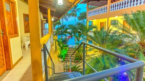 Una escalera conduce a un balcón con vistas a una piscina y palmeras.