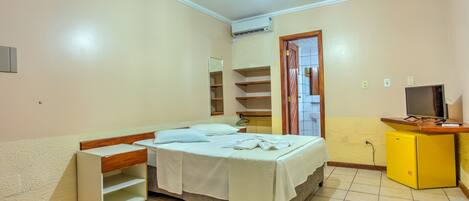 Un dormitorio con cama, mesita de noche, armario, ventilador de techo y televisor.