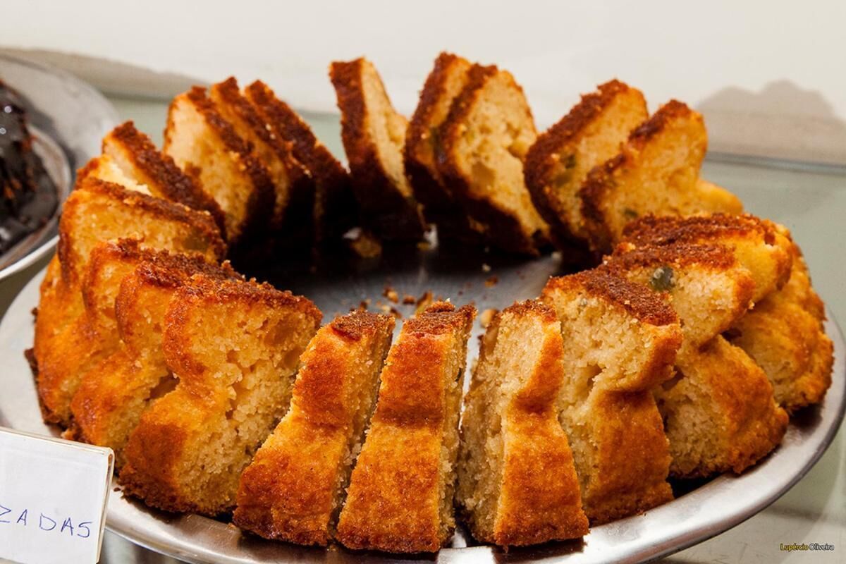 A bundt cake with a golden-brown crust, sliced into wedges, on a metal serving tray.