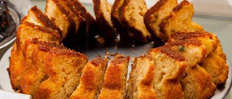 A bundt cake with a golden-brown crust, sliced into wedges, on a metal serving tray.