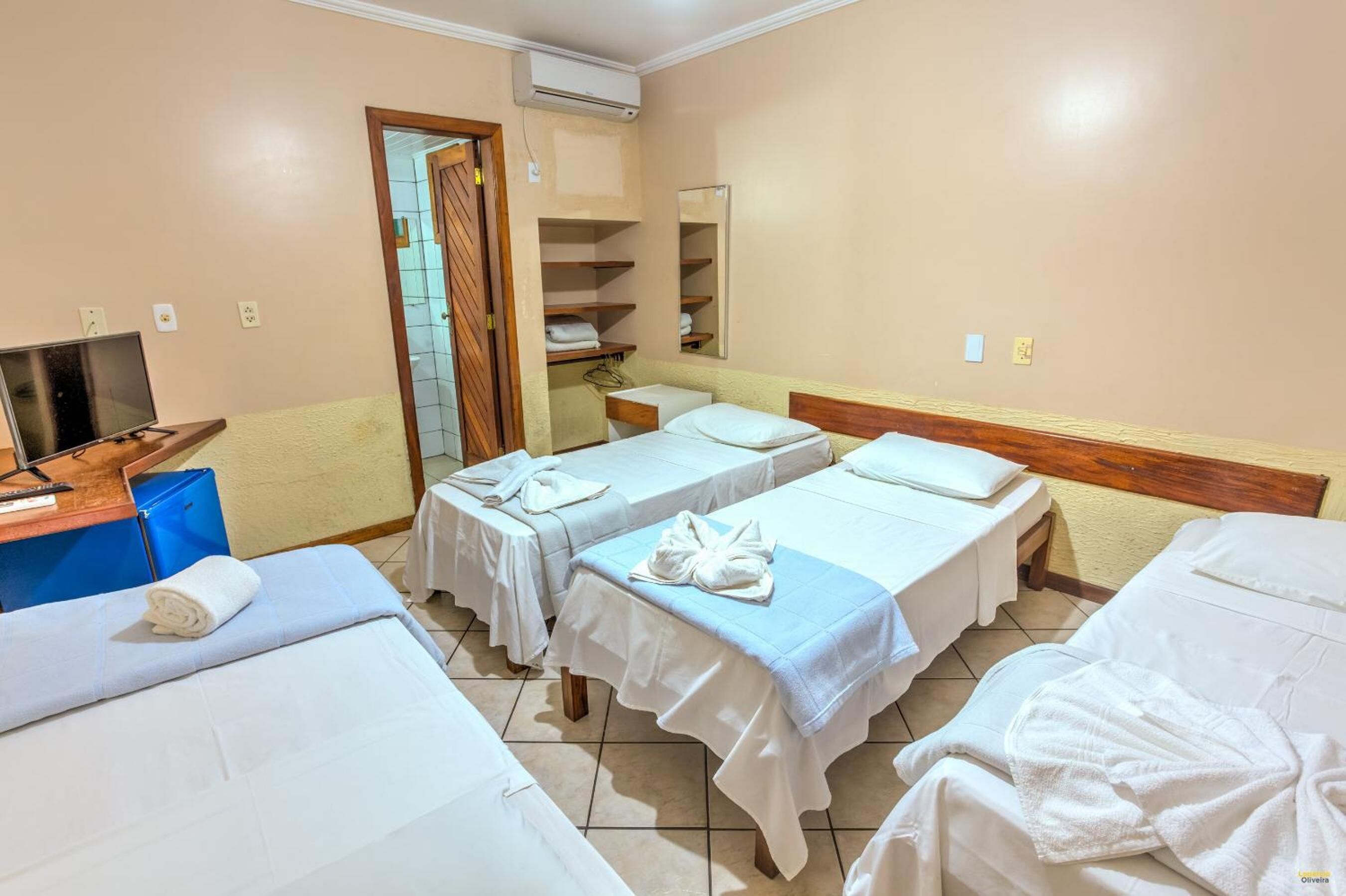 A hotel room with two single beds, a desk with a computer, a wardrobe, and a mirror.