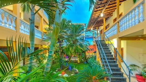 Un atrio interior con un jardín central, una escalera y un edificio de varios niveles con balcones.