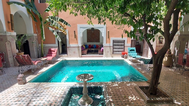 A pool area with a fountain, surrounded by seating and a decorative archway.