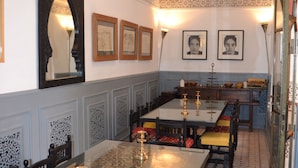 A dining area with a long table, chairs, and a chandelier.