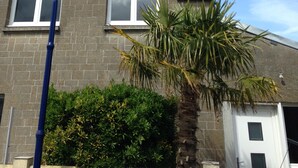 A two-story house with a brick exterior, a red roof, and a white garage door. - RENT THE TY BOUCHOT located between St Malo, Cancale and Mont St Michel (Le Vivier-sur-Mer)