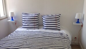 A bed with striped bedding, two bedside tables with lamps, and a window on the left. - RENT THE TY BOUCHOT located between St Malo, Cancale and Mont St Michel (Le Vivier-sur-Mer)