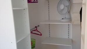 A walk-in closet with white shelving, a fan, and a green basket. - Duplex apartment very well located and quiet (Bretenoux)