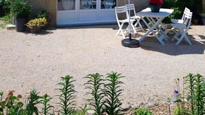 A house with a stone facade, a tiled roof, and a patio with outdoor furniture and a white umbrella. - Duplex apartment very well located and quiet (Bretenoux)