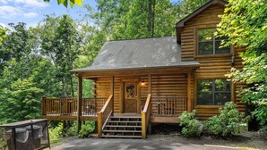 A log cabin with a porch, a staircase, and a deck.