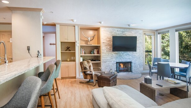 A modern living room with a fireplace, a bar area, and a seating arrangement. - Gateway Plaza R4 2 Bedroom Condo by RedAwning (Vail)