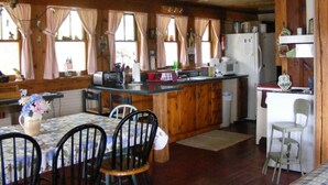 A kitchen with wooden cabinets, a central island, and a dining area with a table and chairs.