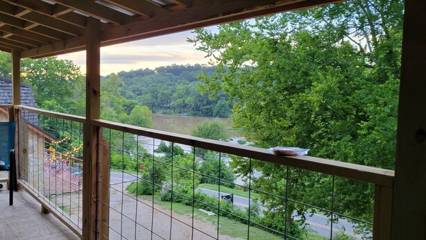 A balcony with a view of a forested area and a road.
