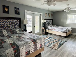 Un dormitorio con dos camas, ventilador de techo y un ventanal grande.