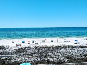 A beach with umbrellas and beach chairs, a clear blue sky, and the ocean.
