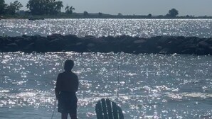 A person fishing by a calm river with a chair and fishing rod on the shore. - Lake Front Cottage Perfect for Fisherman, Birders,  and Family Vacations. (Oak Harbor)