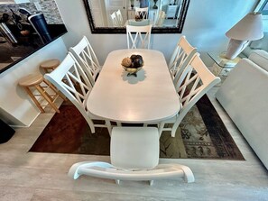 Un comedor con una mesa blanca, sillas blancas y un adorno central.