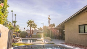 A spa area with hot tubs and palm trees, a building with a window, and a clear sky. - Family Home with Pool, Hot Tub & BBQ near Kierland (Scottsdale)