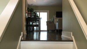 Una escalera de madera oscura con barandillas blancas que conduce a un comedor con mesa y sillas.
