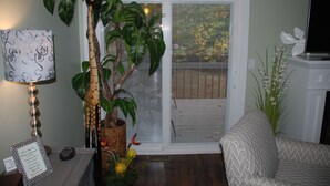 Una sala de estar con un sofá, una lámpara, una planta en maceta y un televisor sobre un mueble.