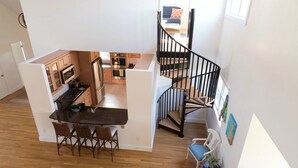 A modern kitchen with wooden cabinets, a black countertop, and a dining area with wicker chairs. - Next Door to Golf Course, Minutes to Beaches! (Middletown)