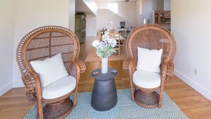 Two wicker chairs with white cushions, a small black table with a vase of flowers, and a blue patterned rug. - Next Door to Golf Course, Minutes to Beaches! (Middletown)