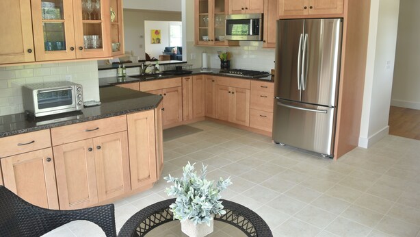 A modern kitchen with wooden cabinets, stainless steel appliances, and a central island with seating. - Next Door to Golf Course, Minutes to Beaches! (Middletown)