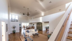 A spacious living area with a high ceiling, a staircase, and a dining area. - Next Door to Golf Course, Minutes to Beaches! (Middletown)