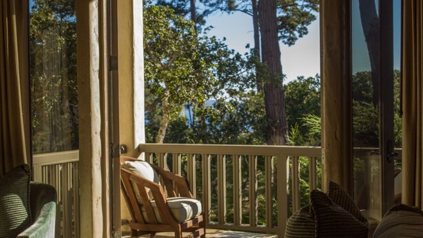 A wooden deck with a chair and cushions, overlooking a forested area. - Forest Opulence: Center of PB Resorts: Four Seasons Beds (Del Monte Forest)