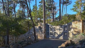 A stone gate leading into a forested area with a paved path. - Forest Opulence: Center of PB Resorts: Four Seasons Beds (Del Monte Forest)