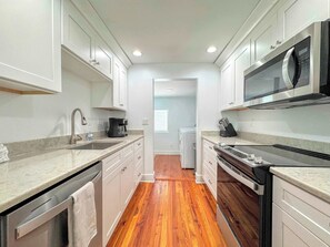 A compact kitchen with white cabinetry, a built-in microwave, and a coffee maker. - 231 Pearl Island Cottage Retreat w Private Pool (Fort Myers Beach)