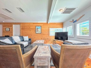 A modern living room with a sofa, a coffee table, and wicker chairs. - 231 Pearl Island Cottage Retreat w Private Pool (Fort Myers Beach)