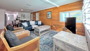 A spacious living area with a sofa set, a coffee table, and a television. - 231 Pearl Island Cottage Retreat w Private Pool (Fort Myers Beach)
