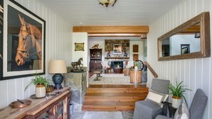 Una sala de estar acogedora con chimenea, piso de madera y un espejo grande.