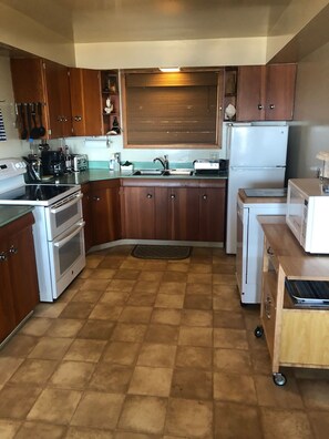 Una cocina compacta con armarios de madera, horno empotrado, refrigerador y microondas.