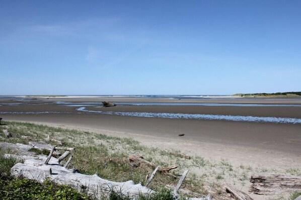 Una playa con una amplia zona arenosa y un primer plano rocoso.