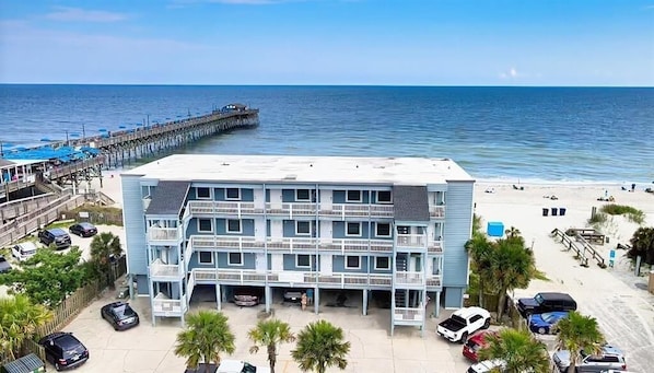 A beachfront hotel with multiple balconies, a pier, and beach access.