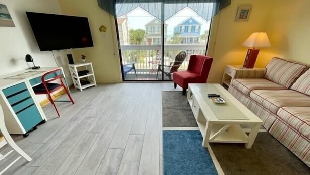 Un salon moderne avec un téléviseur, un fauteuil rouge, un canapé et une table basse.