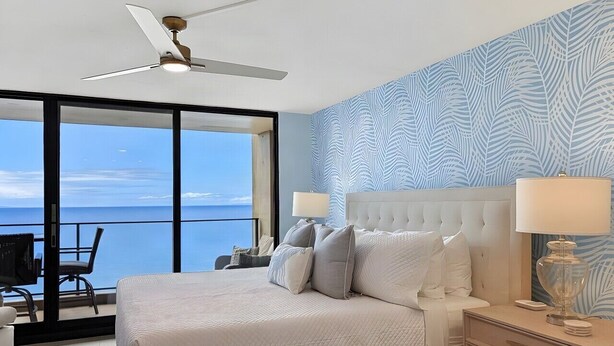 A bedroom with a bed, bedside tables, a ceiling fan, and a view of the ocean. - ❤️ Renovated 8th Floor Studio at The Mahana!! ❤️ (Lahaina)