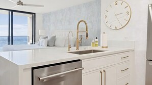 Una cocina moderna con lavavajillas integrado, un ventanal amplio y un reloj de pared.