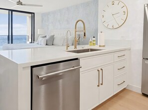 Una cocina moderna con lavavajillas integrado, un ventanal amplio y un reloj de pared.