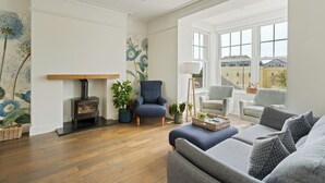Una sala de estar con chimenea, sofás y un ventanal con vistas a edificios.