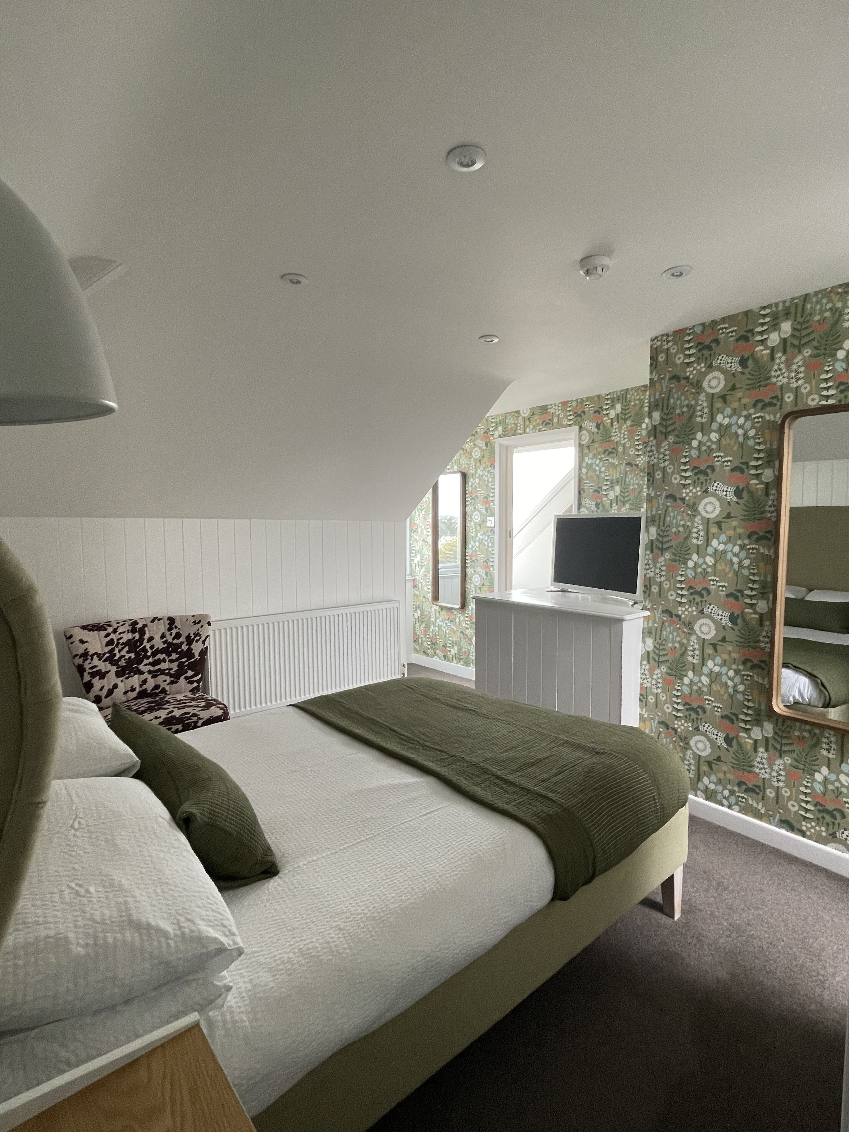 Un dormitorio con cama, televisor, radiador y ventana.